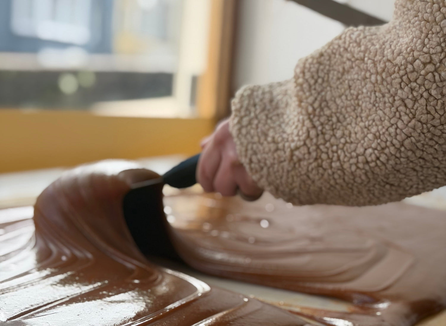 Person spreading chocolate on a surface with a spatula
