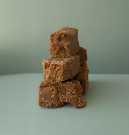Stack of brown fudge pieces on a light green surface with a plain background